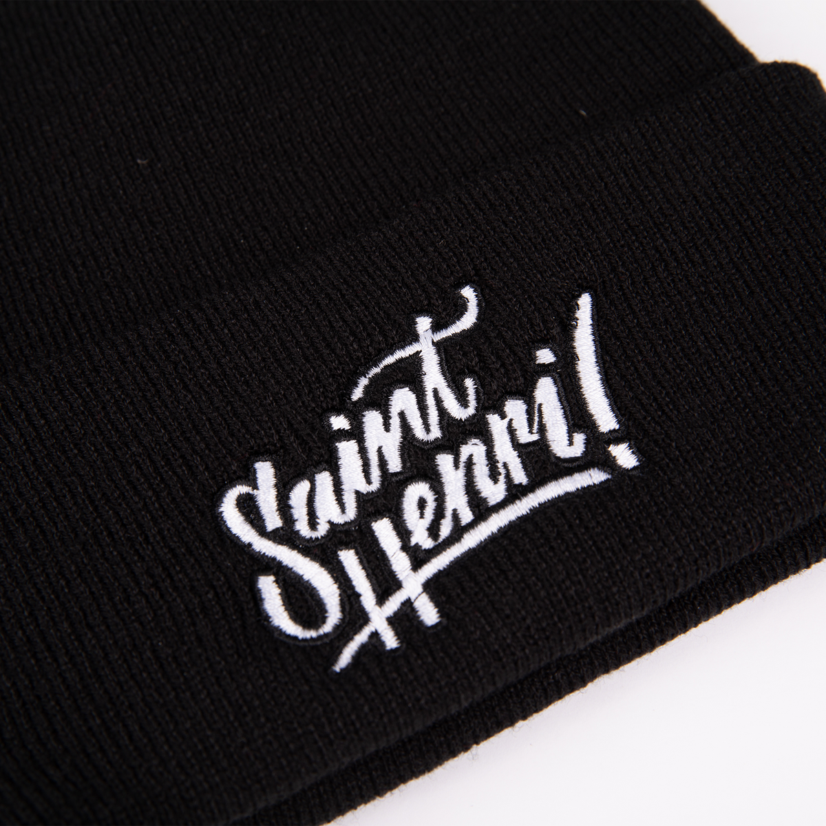 A closeup of a black tuque with the Saint-Henri design embroidered on the front. 