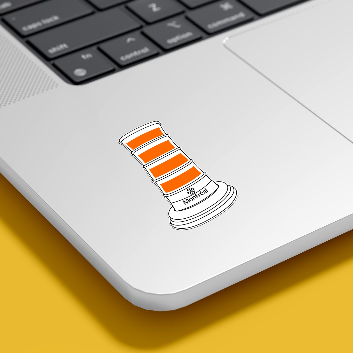 Laptop with a traffic cone sticker on a yellow surface