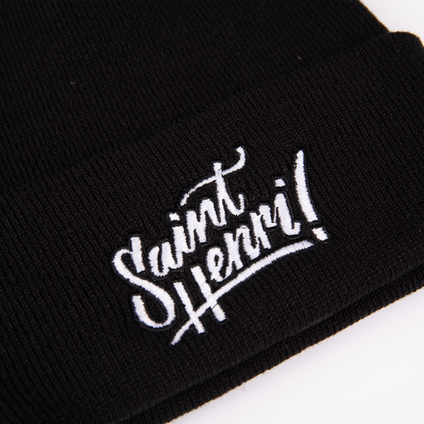 A closeup of a black tuque with the Saint-Henri design embroidered on the front. 
