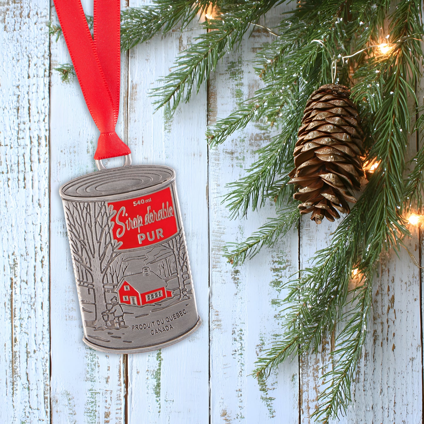 Decorative ornament with a red ribbon and pine cone on a wooden background