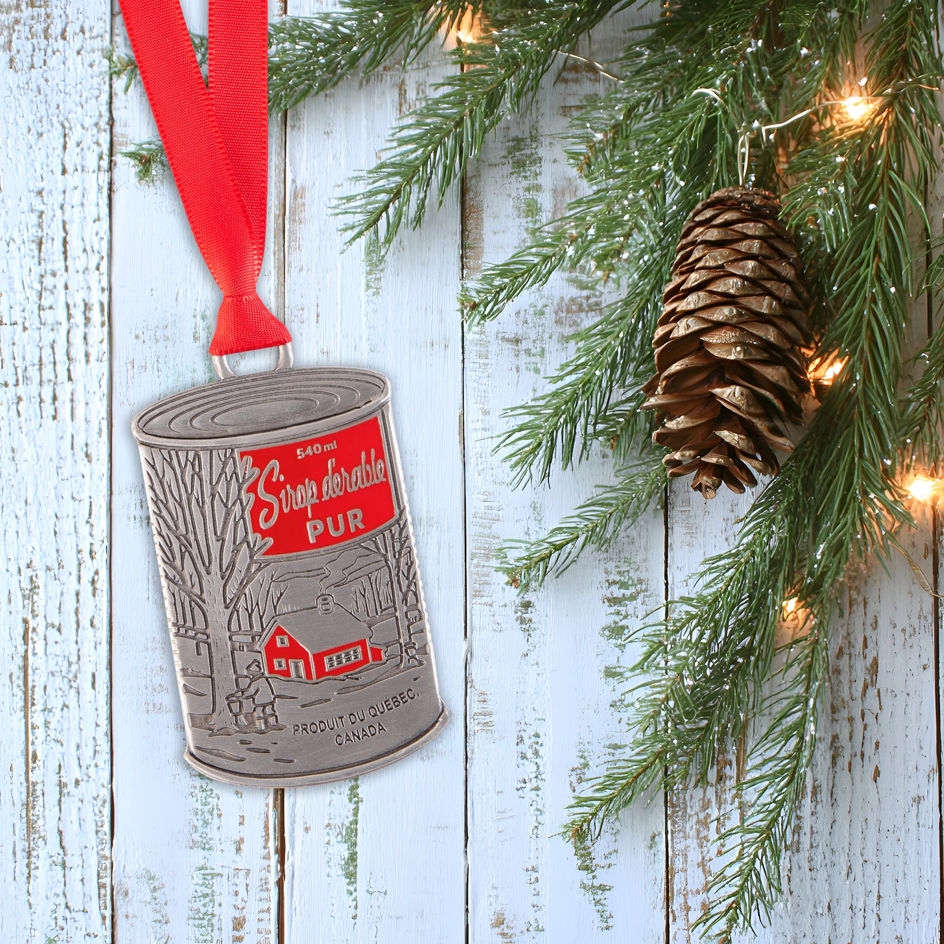 Decorative ornament with a red ribbon and pine cone on a wooden background