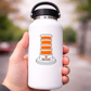 White water bottle with orange cone sticker design held by a hand outdoors